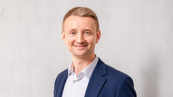 Portrait von Matthias Albrecht im blauen Anzug vor grauer Wand