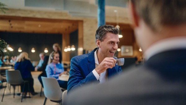Besprechung-an-der-Cafebar-männlicher-Mitarbeiter-lächelnd-im-Fokus