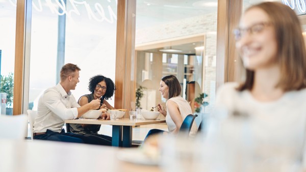 4-junge-Personen-sitzen-zusammen-beim-Mittagessen