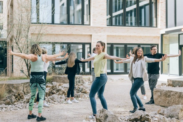 eine-Gruppe-von_Mitarbeiter-machen-Sportübungen-im-Innenhof