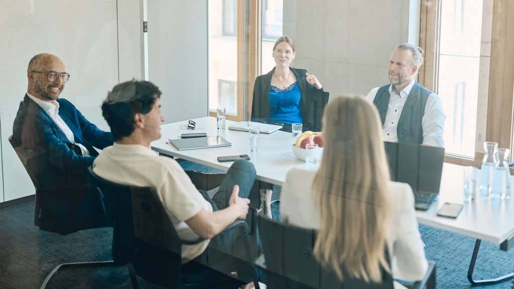 Fünf Mitarbeiter haben eine Teambesprechung im hellen Besprechungsraum auf dem Campus