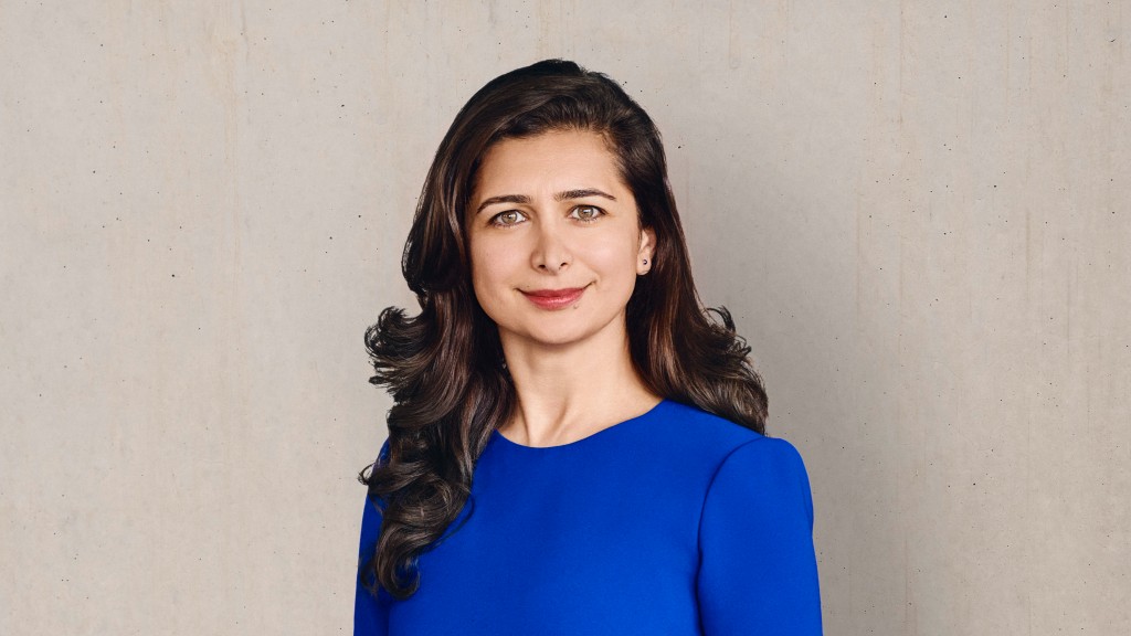 Zeliha Hanning im blauen Kleid vor grauer Wand