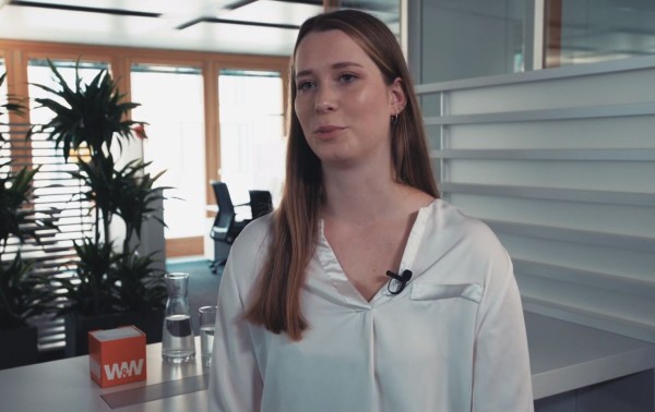 Junge Frau steht in einem Büro im Campus um ein Interview zu geben