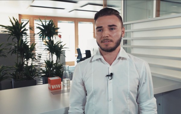 Junger Mann steht in einem Büro im Campus um ein Interview zu geben