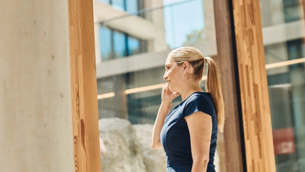 Eine blonde Frau die bei einem Telefonat aus dem Fenster schaut