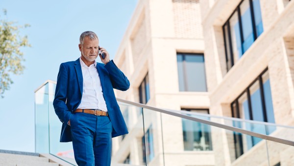 Mann der in einem blauen Anzug die Treppe herunter läuft und telefoniert