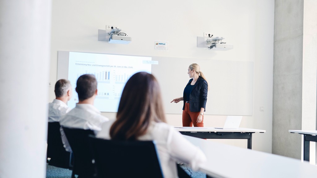 Eine Frau die vor drei Personen einen Weiterbildungsvortrag hält