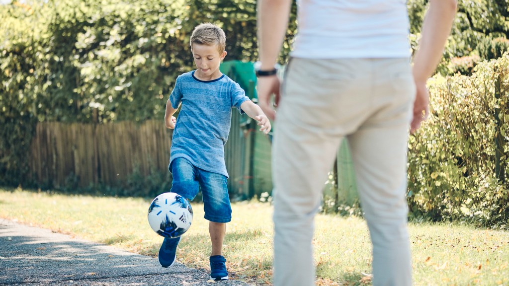 Kleiner Junge der mit einem Erwachsenen Fußball spielt