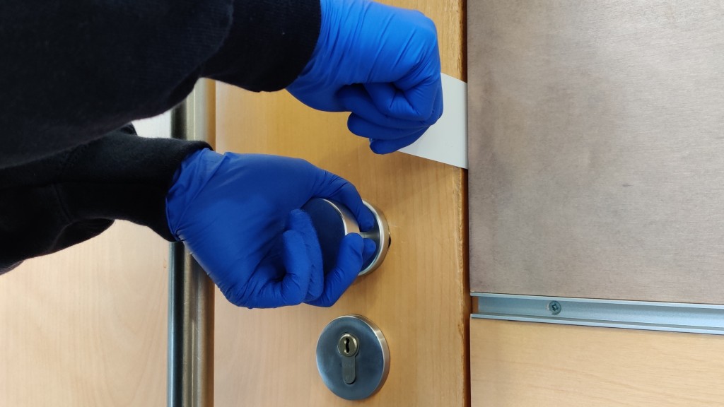 Hände in Handschuhen brechen eine Tür auf