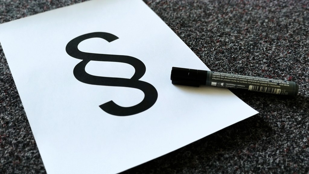 Weißes Blatt mit Paragraph-Zeichen auf dunkelgrauem Teppichboden
