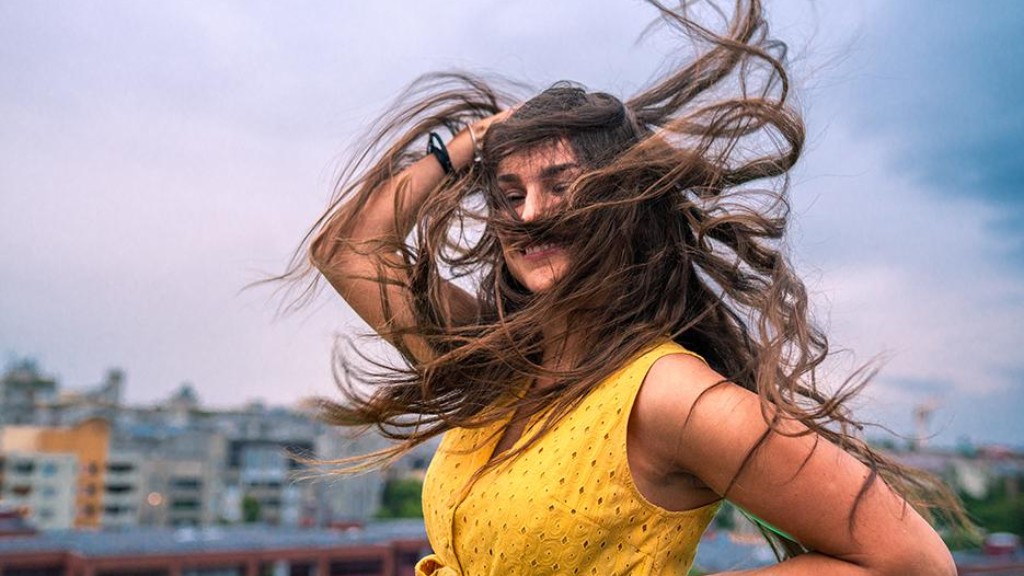 Frau schüttelt im WInd ihre Haare