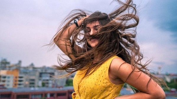Frau schüttelt im WInd ihre Haare