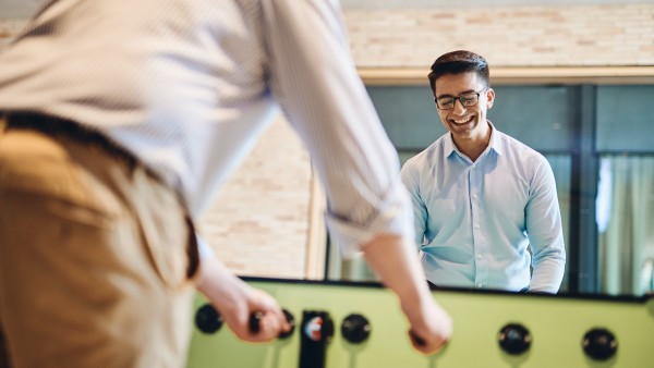 Zwei junge Mitarbeiter spielen an einem Tischkicker