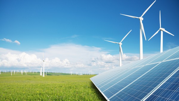 Wind- und Solaranlagen auf einer grünen Wiese mit blauem Himmel
