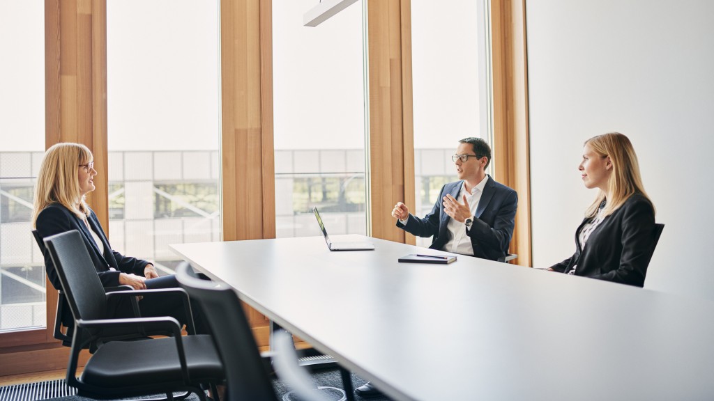 Zwei Frauen und ein Mann sitzen in einem Meeting